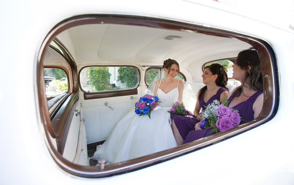 Mariée avec filles d'honneur dans une voiture ancienne