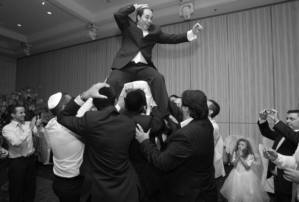 Groom on a chair during hora dance.